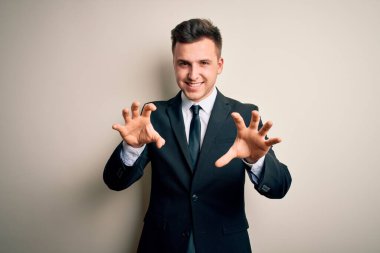 Zarif bir takım elbise ve kravat takan genç yakışıklı bir iş adamı izole edilmiş arka planda komik bir şekilde gülüyor kedi gibi pençe hareketi yapıyor, agresif ve seksi bir ifade.