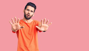 Sakallı, sıradan tişörtlü genç yakışıklı. Avuç içi hareketlerini, sinirli ve hayal kırıklığına uğramış ifadesini durduruyor. 