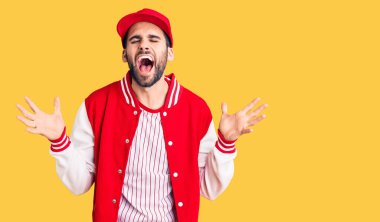 Sakallı, beysbol ceketli, şapkalı, çılgın ve başarıyı kutlayan genç yakışıklı bir adam. Kolları havada, gözleri kapalı, heyecanlı bir şekilde bağırıyor. Kazanan konsept 