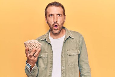 Genç yakışıklı adam elinde nohut kasesi tutuyor. Korkmuş ve şaşkına dönmüş ağzı açık, şaşırmış, inançsız bir yüz. 