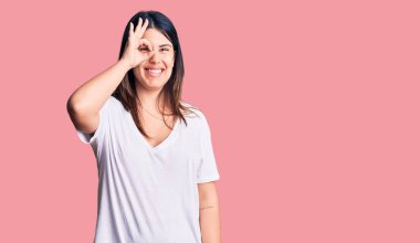 Genç, güzel, esmer, günlük tişört giyen, el hareketleriyle gülümseyen, mutlu yüzüyle parmaklarının arasından bakan bir kadın.. 