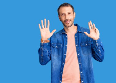 Gündelik kıyafetler giyen genç ve yakışıklı bir adam dokuz numarayı gösterip işaret ederken kendinden emin ve mutlu bir şekilde gülümsüyor.. 