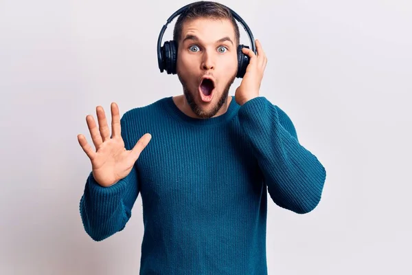 Joven Hombre Guapo Escuchando Música Usando Auriculares Asustados Sorprendidos Con — Foto de Stock