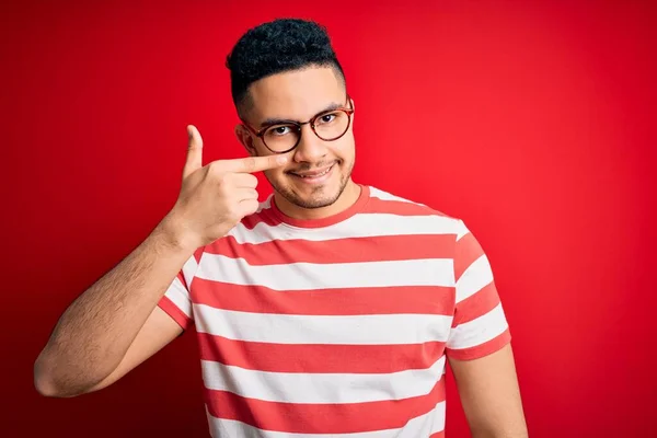 Mladý Pohledný Muž Neformálním Pruhovaném Tričku Brýlích Izolovaném Červeném Pozadí — Stock fotografie