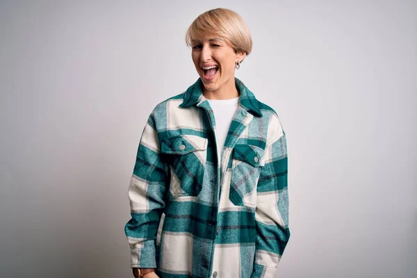 Young blonde woman with short hair wearing casual retro green shirt over isolated background winking looking at the camera with sexy expression, cheerful and happy face.