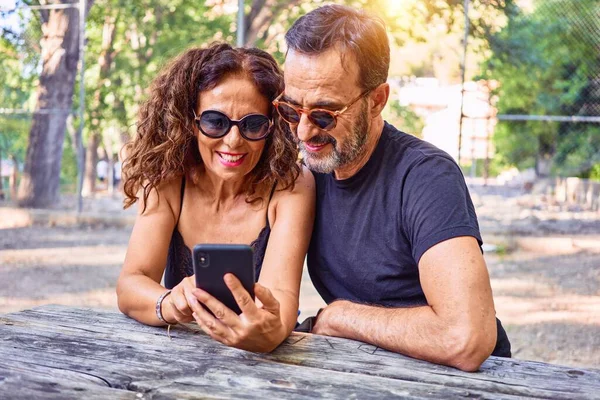 Middelbare Leeftijd Paar Glimlachend Gelukkig Met Behulp Van Smartphone Zittend — Stockfoto