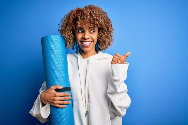 Junge Afrikanisch Amerikanische Sportlerin Hält Yogamatte Über Isoliertem Blauen Hintergrund — Stockfoto