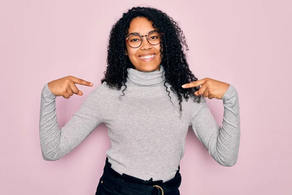 Młoda Afroamerykanka Swetrze Golfem Okularami Różowym Tle Uśmiechem Twarzy Wskazując — Zdjęcie stockowe