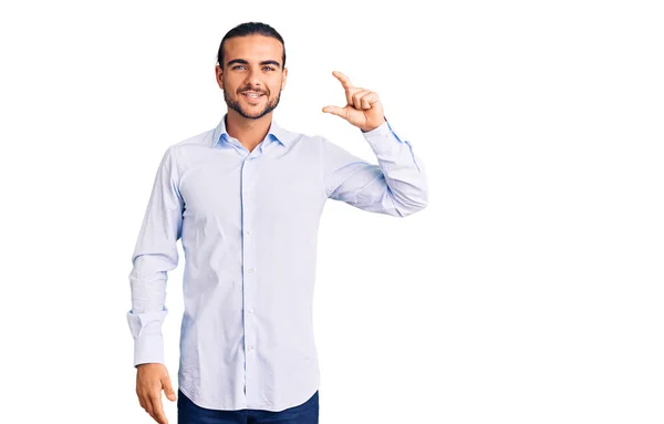 年轻英俊的男人穿着商务服装 面带微笑 自信地做手势 手拿着小尺寸的标志 手拿着手指 手拿着相机 计量概念 — 图库照片
