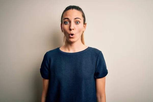 Young beautiful blonde woman with blue eyes wearing casual t-shirt over white background afraid and shocked with surprise expression, fear and excited face.