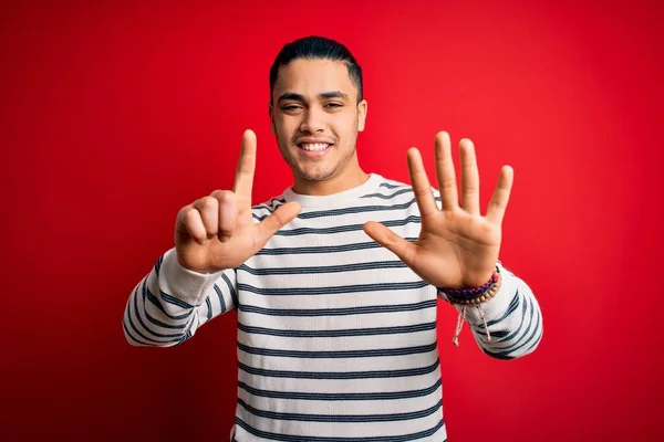 Jovem Brasileiro Vestindo Camiseta Listrada Casual Sobre Fundo Vermelho Isolado — Fotografia de Stock