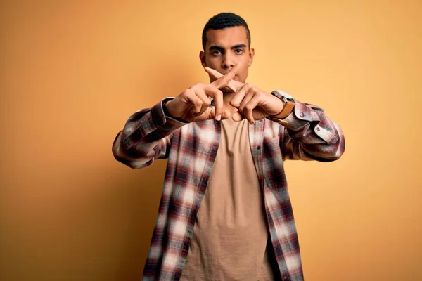 身穿休闲衫站在黄色背景下的年轻英俊的非洲裔美国男子 手指交叉表示拒绝 做阴性手势 — 图库照片
