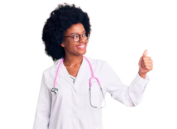 医師のコートと聴診器を身に着けている若いアフリカ系アメリカ人女性は誇りに思って 笑顔で親指を横にジェスチャーアップ — ストック写真