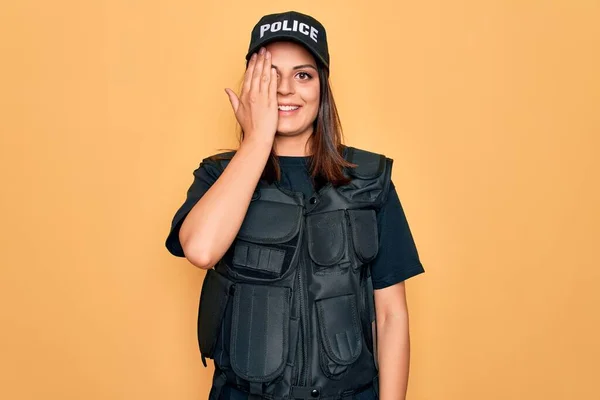 年轻美丽的黑发女警察 身穿警服 头戴防弹帽 一只眼睛蒙着 脸上挂着自信的微笑 感情令人惊讶 — 图库照片
