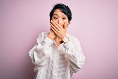 İzole edilmiş pembe arka planda duran sıradan tişörtler giyen genç, güzel Asyalı kız yanlışlıkla ağızlarını kapatarak şok geçirdi. Gizli konsept.