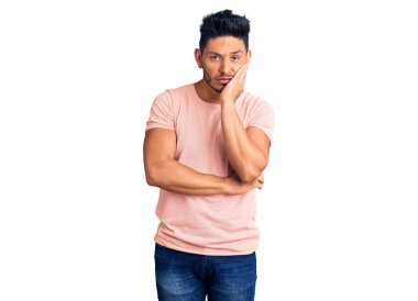 Yakışıklı Latin Amerikalı sıradan giyinen genç adam kollarını kavuşturup depresyondan sıkılmış ve yorgun görünüyor.. 