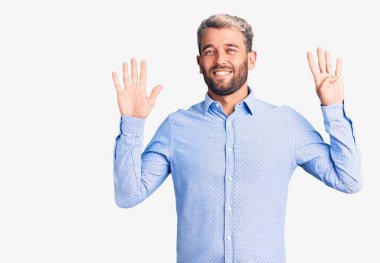 Zarif bir tişört giyen yakışıklı genç adam dokuz numaralı parmaklarını gösterip işaret ederken kendinden emin ve mutlu gülümsüyor.. 