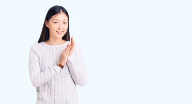 Genç, güzel Çinli kadın, sıradan bir süveter giyer, alkışlar ve mutlu, mutlu ve gururlu elleri bir arada alkışlar. 