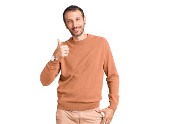 Gündelik giysiler giyen genç yakışıklı adam elleriyle mutlu bir jest yapıyor. Kameraya bakıp başarıyı gösteren ifade. 