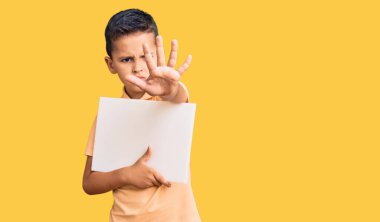 Küçük şirin çocuk elinde boş bir pankartla elinde dur işareti ile ciddi ve kendinden emin bir ifadeyle savunma jesti yapıyor. 