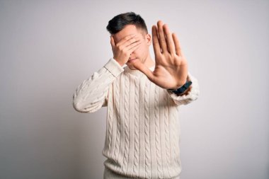 Beyaz tenli arka plan üzerine sıradan bir kazak giyen genç, yakışıklı beyaz bir adam ellerle gözlerini kapatıyor ve hüzünlü ve korku dolu bir ifadeyle dur hareketi yapıyor. Utanç verici ve olumsuz bir kavram..