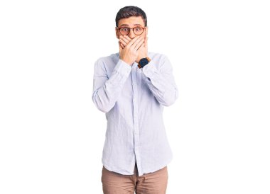 Zarif iş gömleği ve gözlük takan yakışıklı genç adam ağzını yanlışlıkla ellerle kapatmış. gizli kavram. 