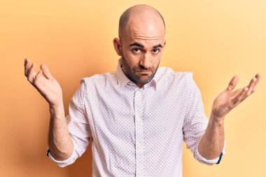 Zarif tişört giyen yakışıklı kel adam habersiz ve kolları açık, hiçbir fikrim yok ve şüpheli bir yüzüm var.. 