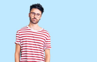 Günlük kıyafetler giyen genç İspanyol adam yüzünde ciddi bir ifadeyle rahatlamış. Basit ve doğal bir şekilde kameraya bakıyorsun.. 