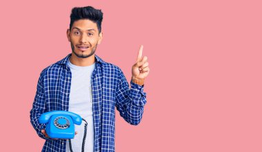 Yakışıklı Latin Amerikalı genç adam elinde antika bir telefon tutarken bir fikre ya da soru işaretine şaşırdı. 