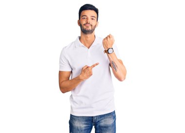 Genç, yakışıklı, günlük kıyafetler giyen, acele eden, saati, sabırsızlığı gösteren, rahat bir ifadeyle kameraya bakan bir İspanyol. 