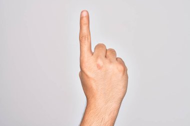 Beyaz arka planda parmaklarını gösteren beyaz tenli bir adamın eli işaret parmağı kullanarak bir numarayı sayıyor. Fikir ve anlayış gösteriyor.