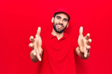 Sakallı, polo giyen ve şapkalı genç yakışıklı bir adam kucak için gülümseyen kameraya bakıyor. Mutluluğu kucaklayan neşeli bir ifade.. 