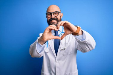 Sakallı, mavi arka planda steteskop takan yakışıklı, kel bir doktor. Aşkla gülümsüyor, elleriyle kalp sembolü yapıyor. Romantik konsept.