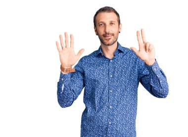 Gündelik kıyafetler giyen genç yakışıklı adam 8 numarayı gösterip işaret ederken kendinden emin ve mutlu bir şekilde gülümsüyor.. 