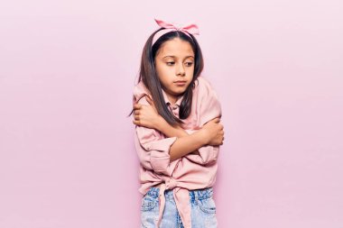 Güzel bir kız çocuğu günlük giysiler giyiyor. Kış soğuğu için titriyor ve donuyor. Yüzünde üzgün ve şok ifadesi var. 