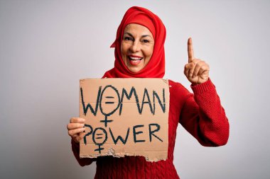 Müslüman tesettürlü orta yaşlı bir kadın elinde bir fikir ya da soru işareti olan mutlu yüzle kadın hakları sorar.