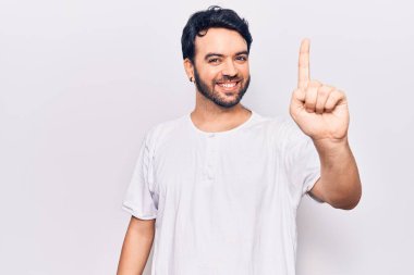 Gündelik kıyafetler giyen genç İspanyol bir numarayı gösterip işaret ederken kendinden emin ve mutlu bir şekilde gülümsüyor.. 