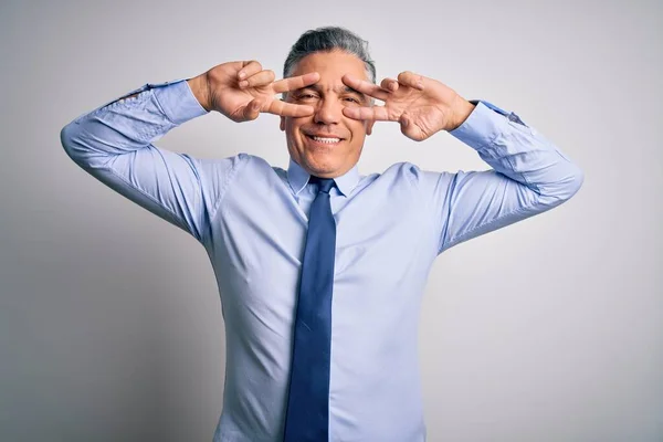 Middle age handsome grey-haired business man wearing elegant shirt and tie Doing peace symbol with fingers over face, smiling cheerful showing victory