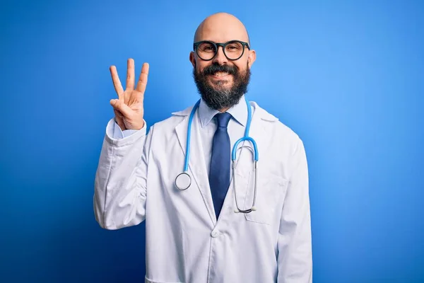 英俊的秃头医生 留着胡子 戴着眼镜 带着听诊器 带着蓝色背景 三指一指 面带微笑 自信而快乐 — 图库照片