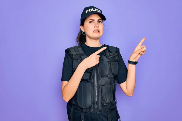 Young police woman wearing security bulletproof vest uniform over purple background Pointing aside worried and nervous with both hands, concerned and surprised expression