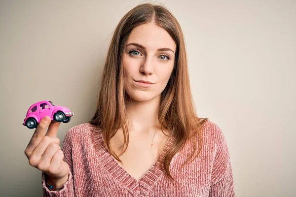 Jovem Mulher Ruiva Bonita Segurando Pequeno Carro Rosa Sobre Fundo — Fotografia de Stock