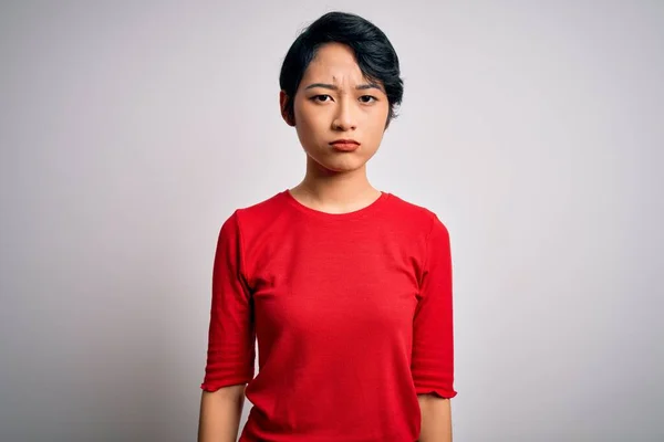 若い美しいアジアの女の子のカジュアルな赤いTシャツを着て隔離された白い背景の上に立って落ち込んで苦痛を心配し 怒っていると恐れて泣いている 悲しい表情 — ストック写真