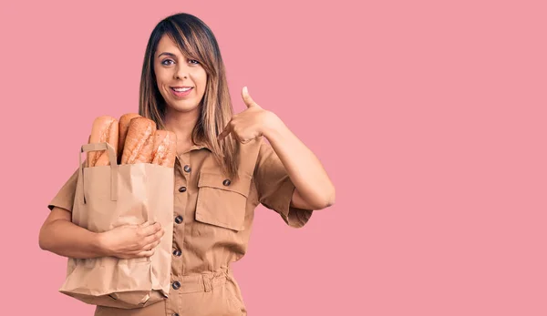 Joven Hermosa Mujer Sosteniendo Bolsa Papel Con Pan Señalando Dedo — Foto de Stock
