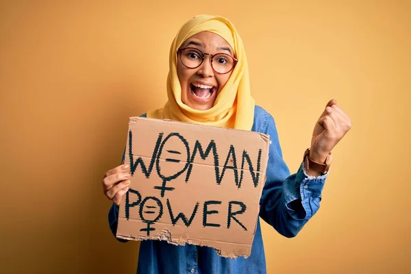 ムスリムのヒジャーブを身に着けている巻き毛を持つ美しい女性は 誇りと勝利と成功を祝う叫びバナーを保持する女性の権利を求めて非常に興奮し 感情を応援 — ストック写真