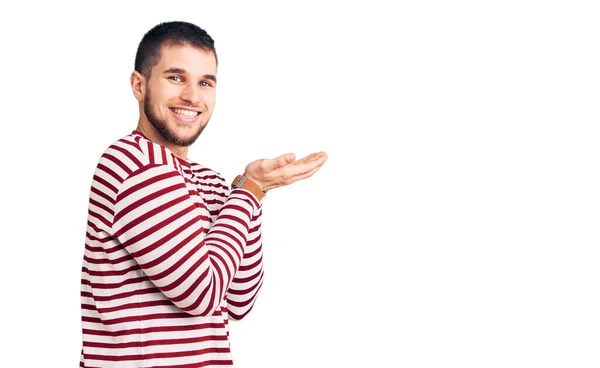 Young Handsome Man Wearing Striped Sweater Pointing Aside Hands Open — Stock Photo, Image