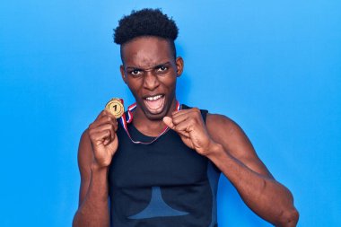 Afro-Amerikalı genç adam spor giysisi takıyor elinde madalyayla sinirlenmiş ve sinirlenmiş bir şekilde bağırıyor, öfkeyle çılgınca bağırıyor ve el kaldırıyor. 