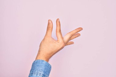 İzole edilmiş pembe arka plan üzerinde parmaklarını gösteren beyaz bir adamın eli. Görünmez bir şeyi alıp, parmaklarıyla uzayı gösteren bir nesneyi tutuyor.