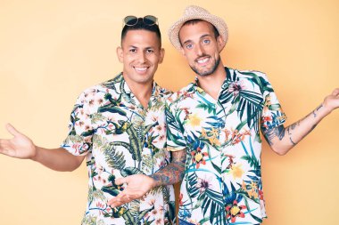 İki genç eşcinsel adam yaz şapkası ve Hawaii gömleği giyip gülümsüyor. Avuçlarını açıp gülümsüyor. Karşılaştırma ve reklam karşılaştırması yapıyorlar. 