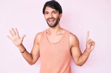 Yakışıklı İspanyol adam gündelik giysiler giyip altı numarayı gösterip işaret ederken kendinden emin ve mutlu gülümsüyor.. 