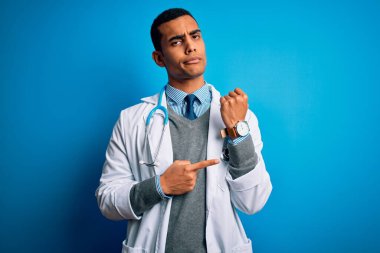Mavi arka plan üzerinde steteskop ve ceket giyen yakışıklı Afro-Amerikan doktor. Saati, sabırsızlığı izlemek için acele ediyor ve rahat bir ifadeyle kameraya bakıyor.